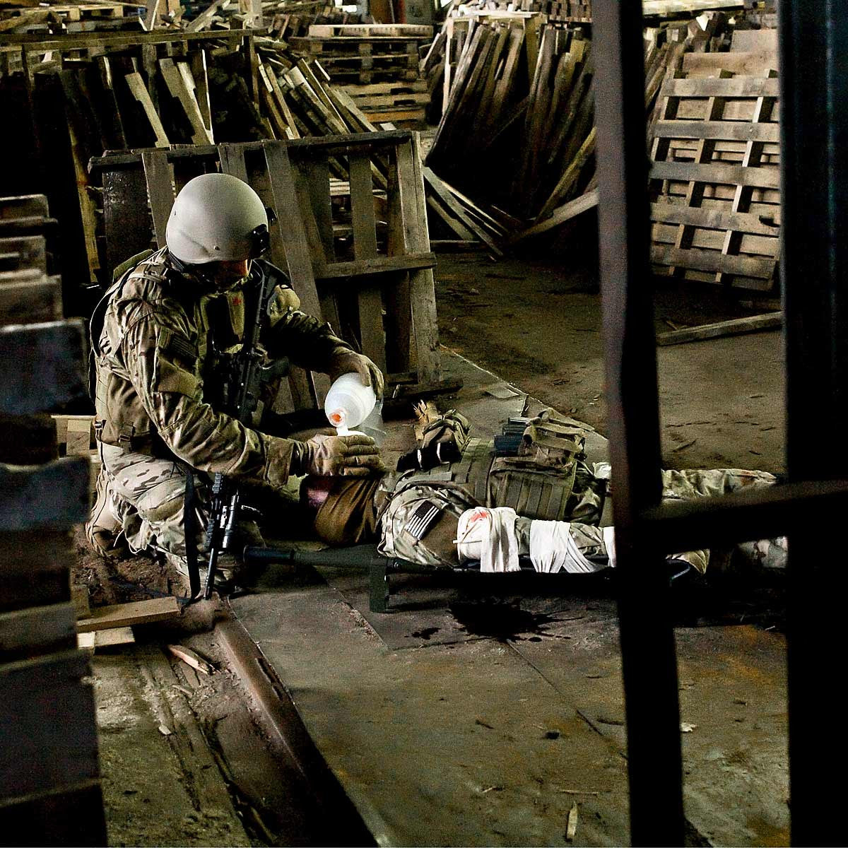 Wide view of a soldier using the Pocket BVM™ to administer manual resuscitation to another fallen soldier.